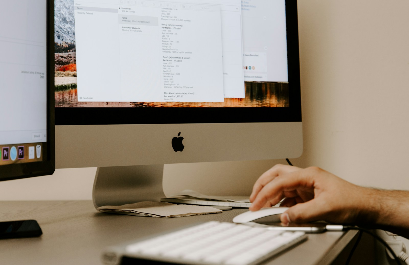 person holding white Apple Magic Mouse beside iMac and keyboard